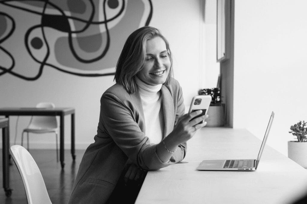 Person smiling looking at phone at desk